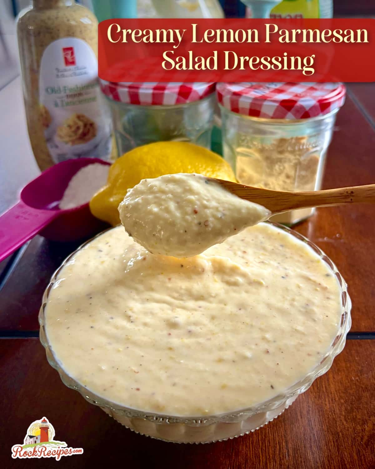Photo of a wooden spoon dipping into Creamy Lemon Parmesan Salad Dressing with title text and rock recipes logo added for Pinterest and social media posts.