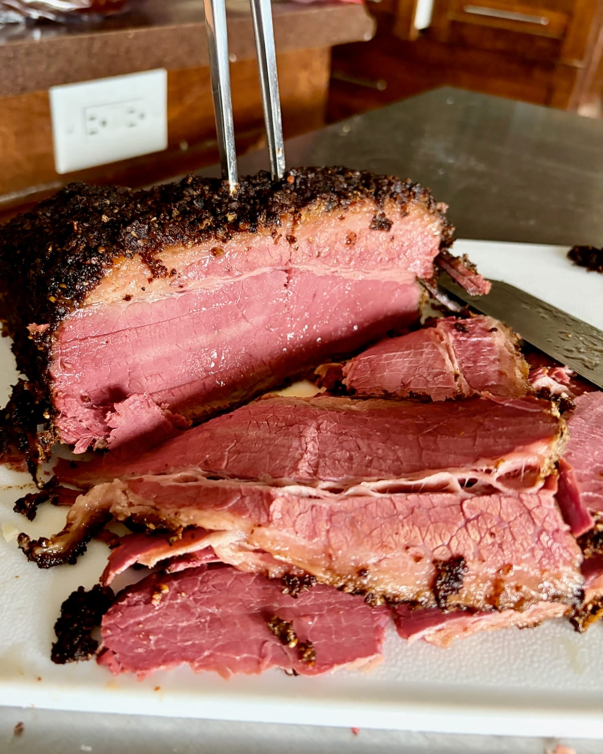 Homemade Montreal Smoked Meat being sliced on a cutting board.