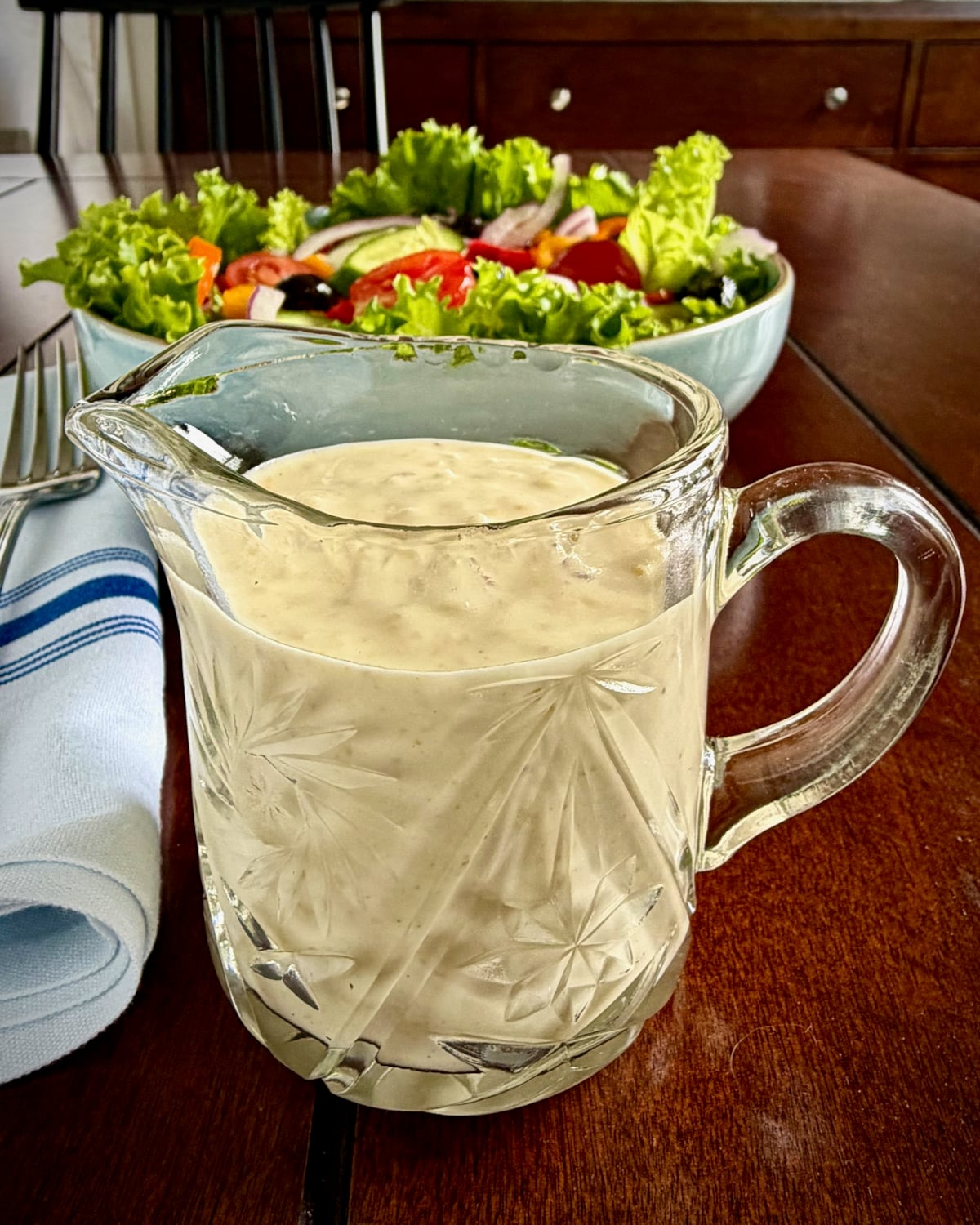 Close up photo of Creamy Lemon Parmesan Salad Dressing in a crystal jug dispenser.