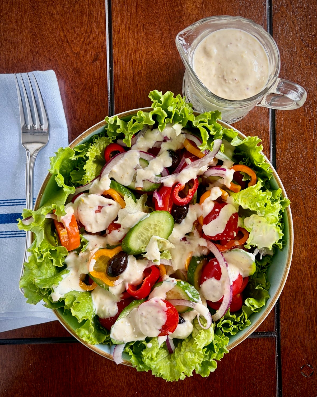 Overhead photo of a salad with Creamy Lemon Parmesan Salad Dressing drizzled on.