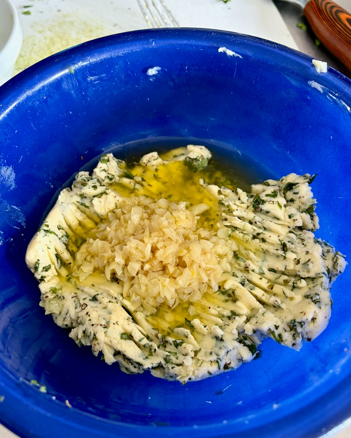 Photo of cooked garlic being added to the herbed butter.