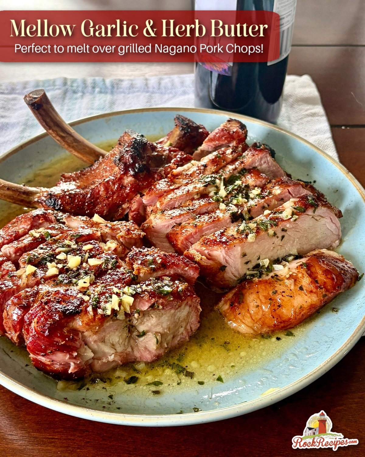 Garlic Herb Butter, photo showing butter melted over smoked and grilled Nagano Pork Chops with title text added fro Pinterest and social media posts.