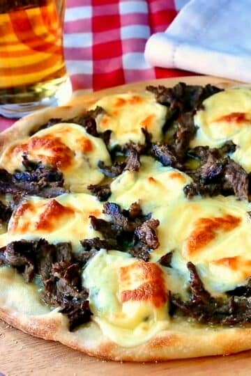 Philly Cheesesteak Pizza shown uncut in a wooden pizza peel.