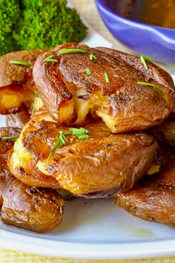 Smash Roasted Potatoes pictured stacked on a white plate.