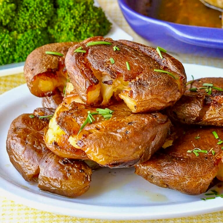 Smash Roasted Potatoes pictured stacked on a white plate.