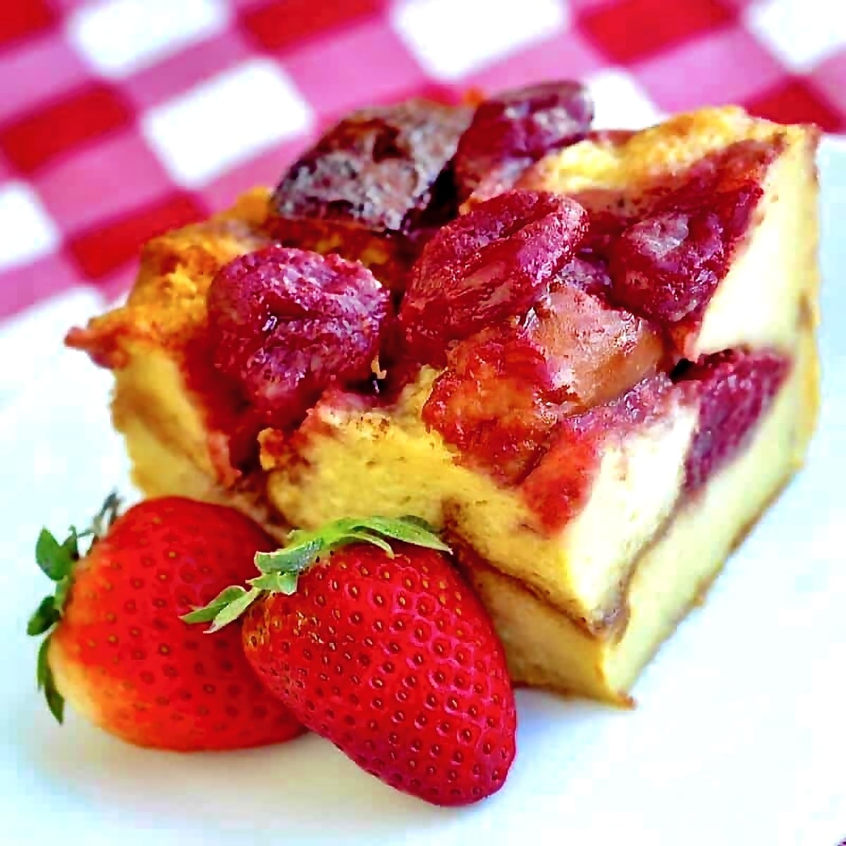 Strawberries & Cream Bread Pudding close up photo of a single serving on a white plate