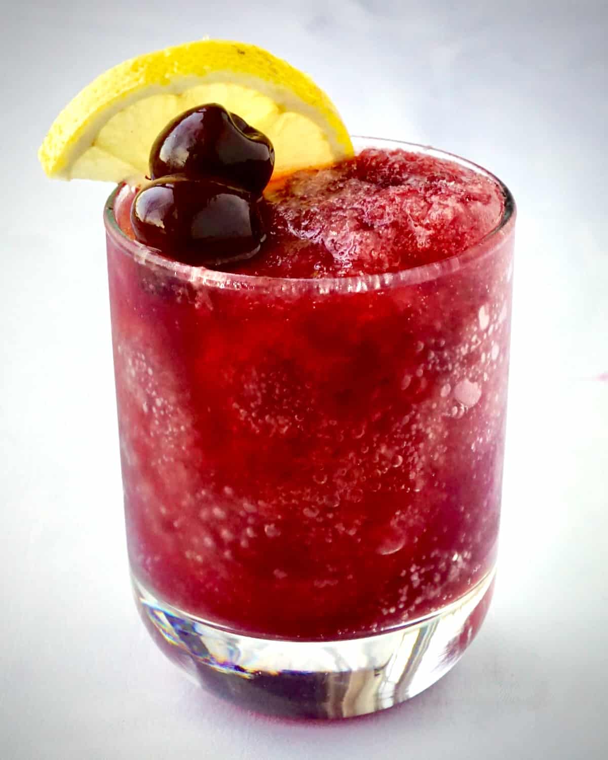 Cherry Vodka Slush photo of one full glass against a pure white background.