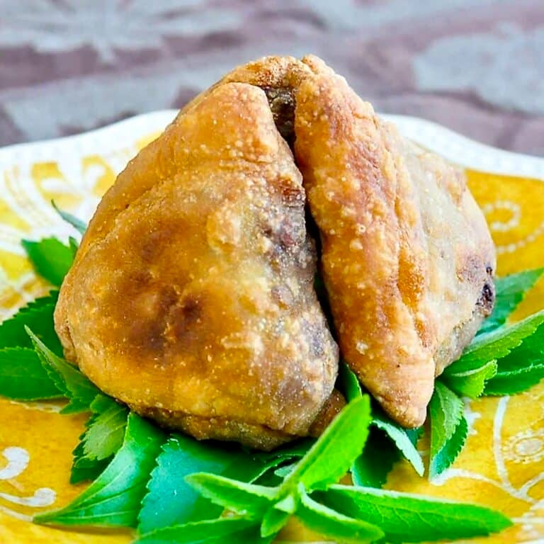 The Best Beef Samosas photo of garnished samosas on a yellow plate.