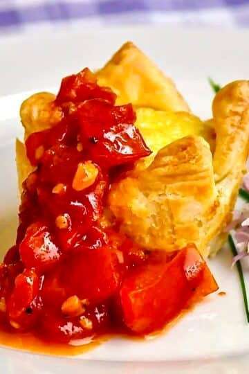Parmesan Fennel Mini Quiche with Spicy Quick Tomato Compote. Close up photo of one serving on a white plate with chive flower garnish.