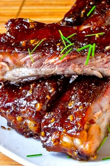 Close up photo of Honey Garlic Sticky Ribs stacked on a white plate