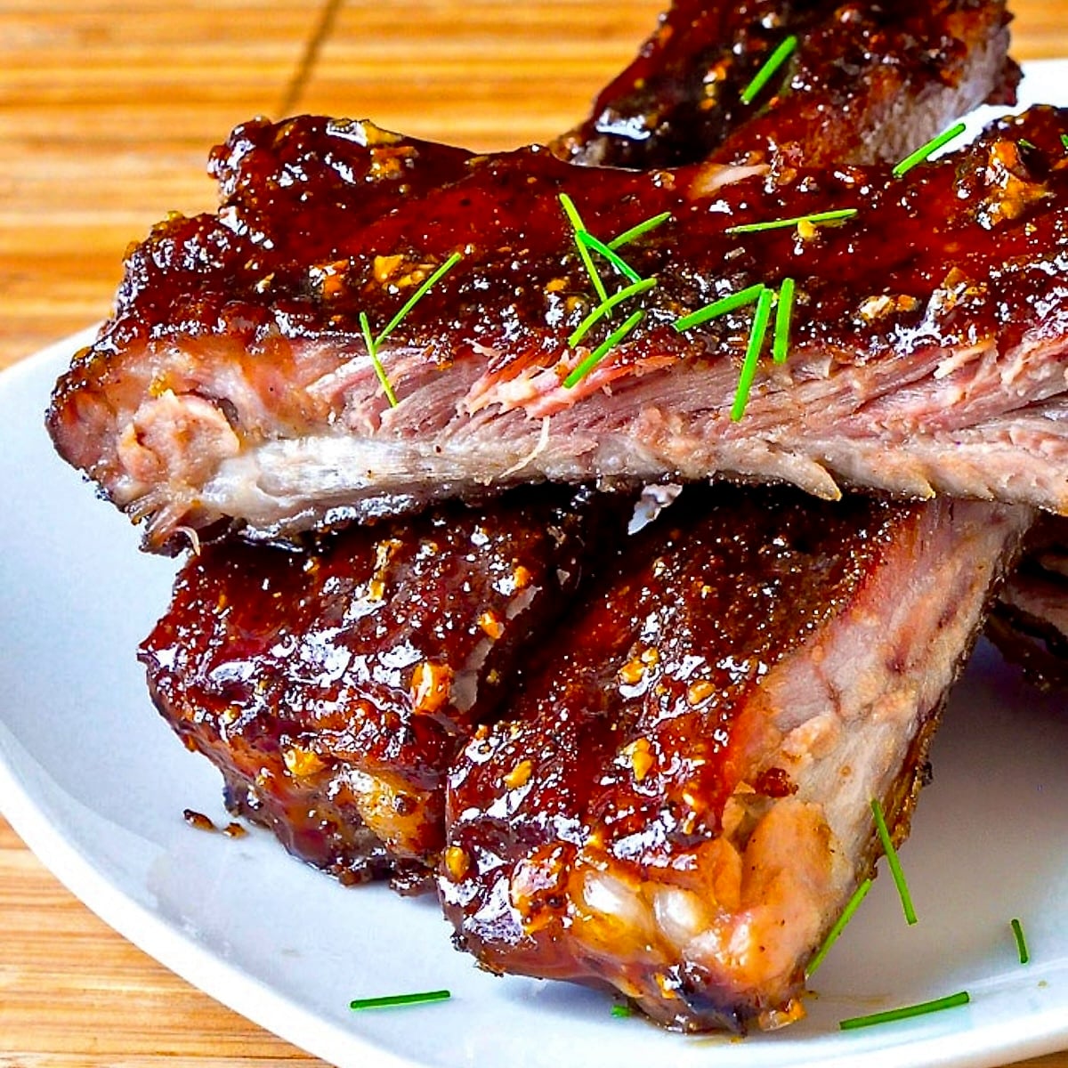 Close up photo of Honey Garlic Sticky Ribs stacked on a white plate
