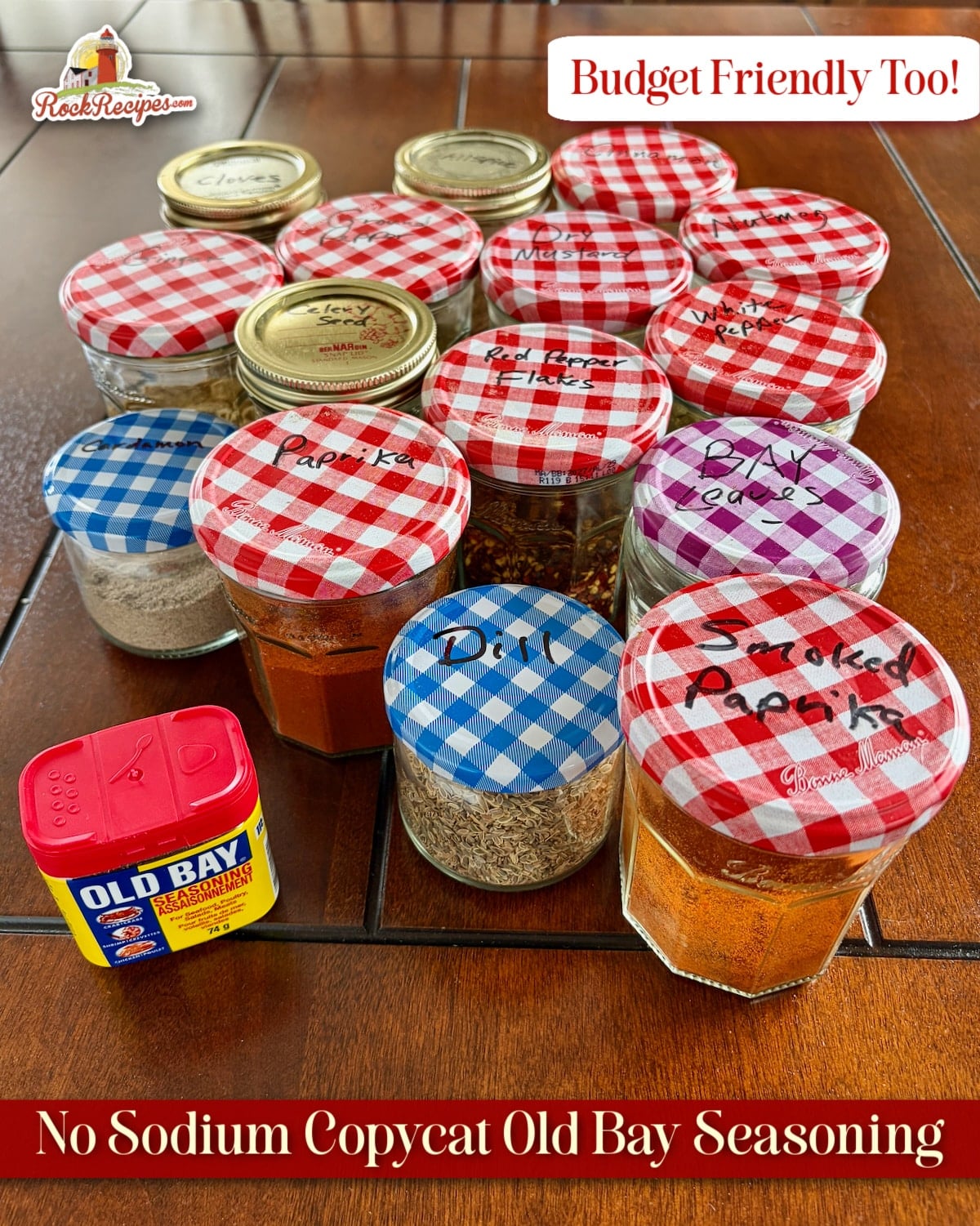 Photo of all the herbs and spices needed for Copycat Old Bay Seasoning in mason jars with a canister of Old Bay Seasoning in the foreground with title text added fro Pinterest and social media posts.