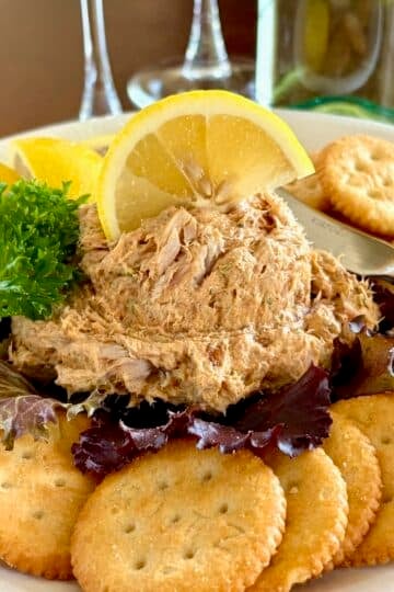 Close up photo of a scoop of Smoked Fish Dip served as an appetizer with lemon slices and Ritz Crackers square cropped for Google featured image.
