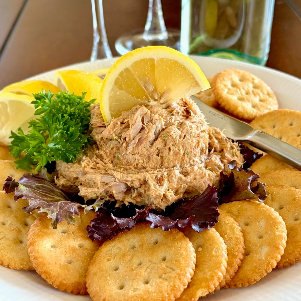 Close up photo of a scoop of Smoked Fish Dip served as an appetizer with lemon slices and Ritz Crackers square cropped for Google featured image.