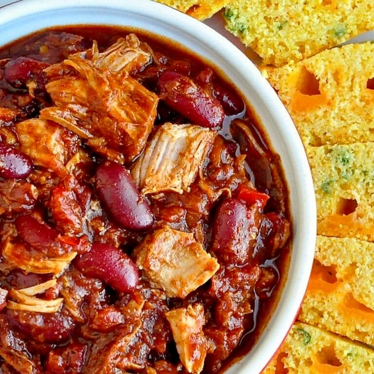 Pulled Pork Chili with Cheddar Green Onion Cornbread close up overhead photo of one serving in a white bowl.