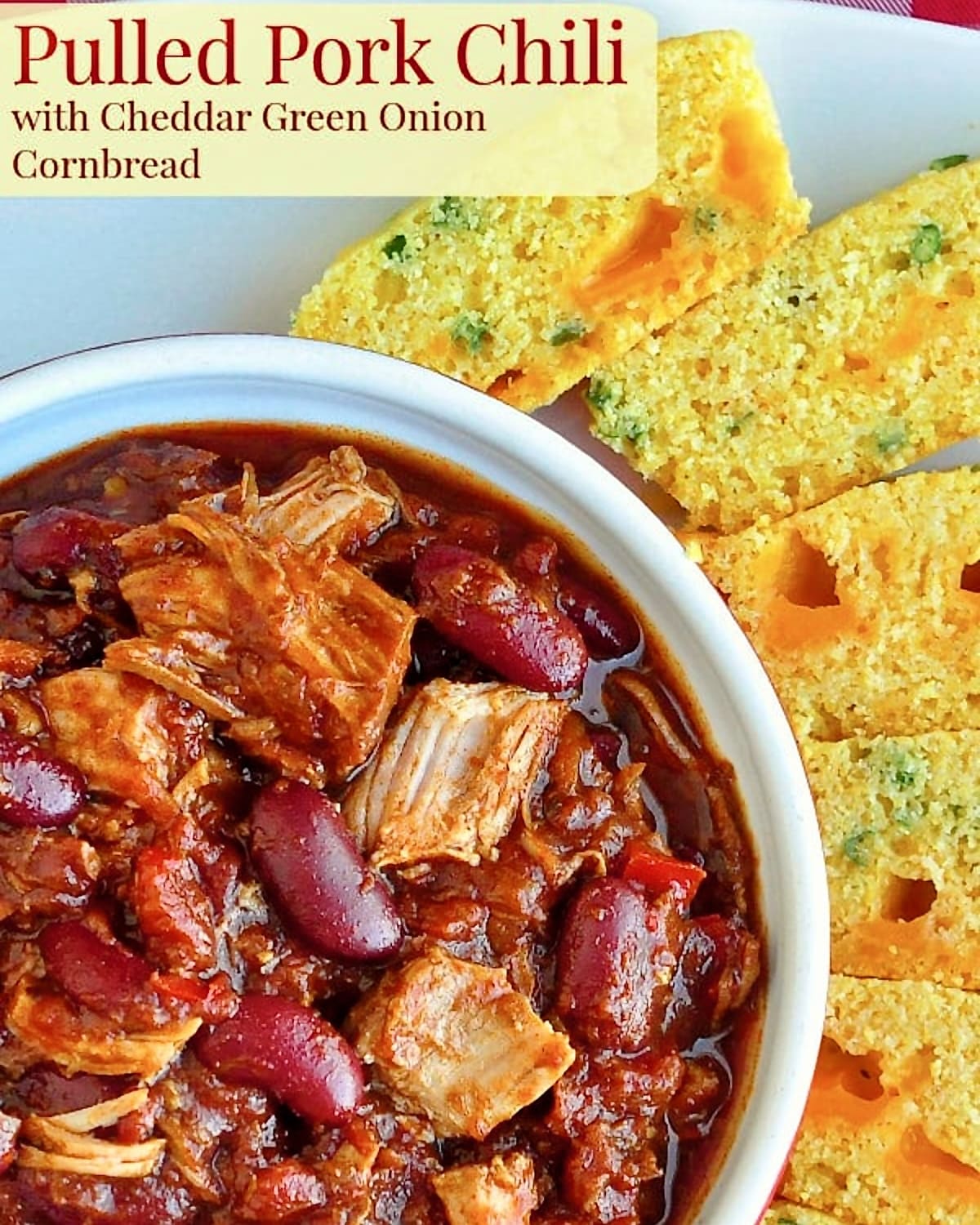 Pulled Pork Chili with Cheddar Green Onion Cornbread close up overhead photo of one serving in a white bowl with title text added for Pinterest and social media posts.
