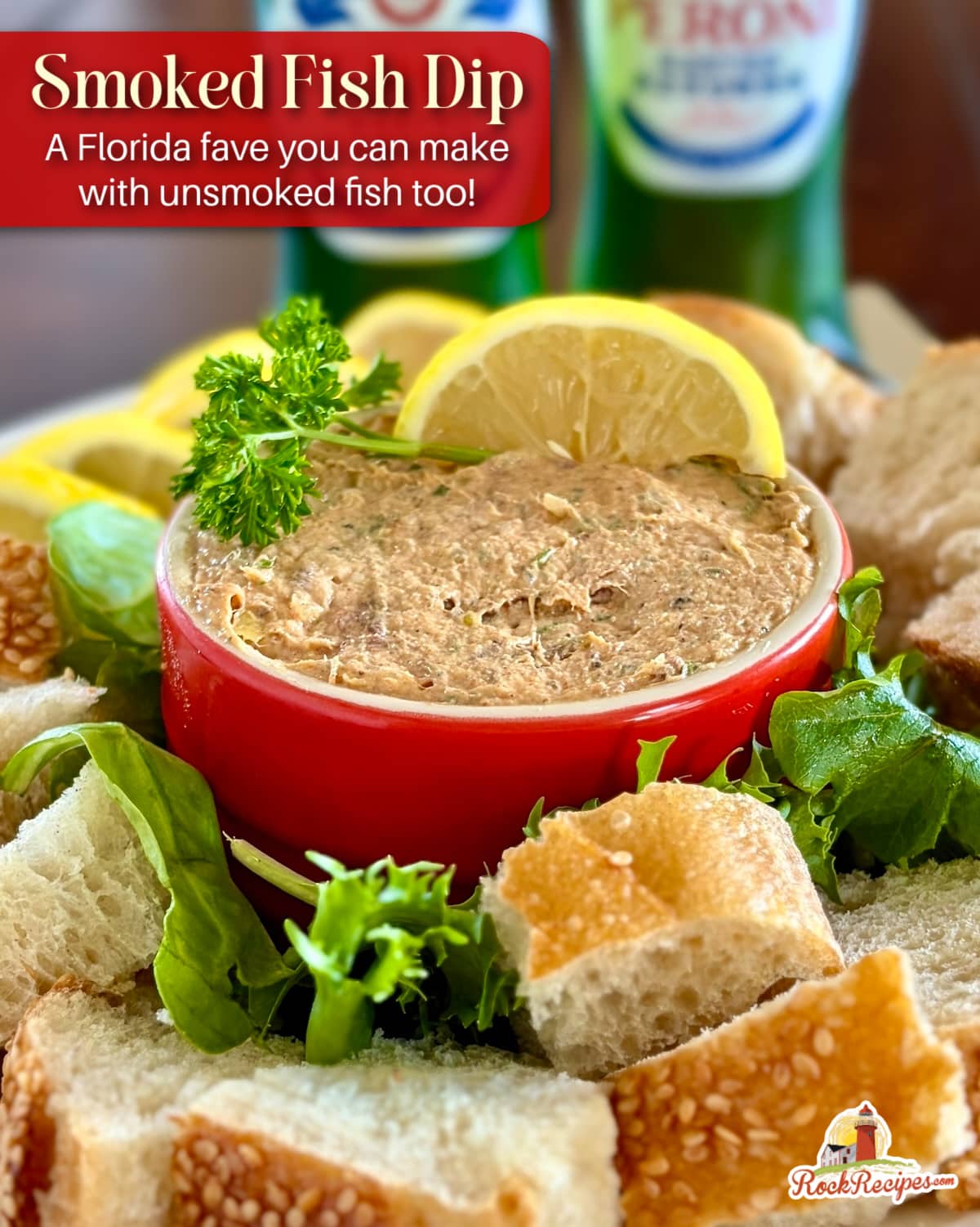 Close up photo of Smoked Fish Dip in a red ramekin with lemon slices, parsley and bread chunks. This photo has the post title text and Rock Recipes logo added for Pinterest and social media posts.