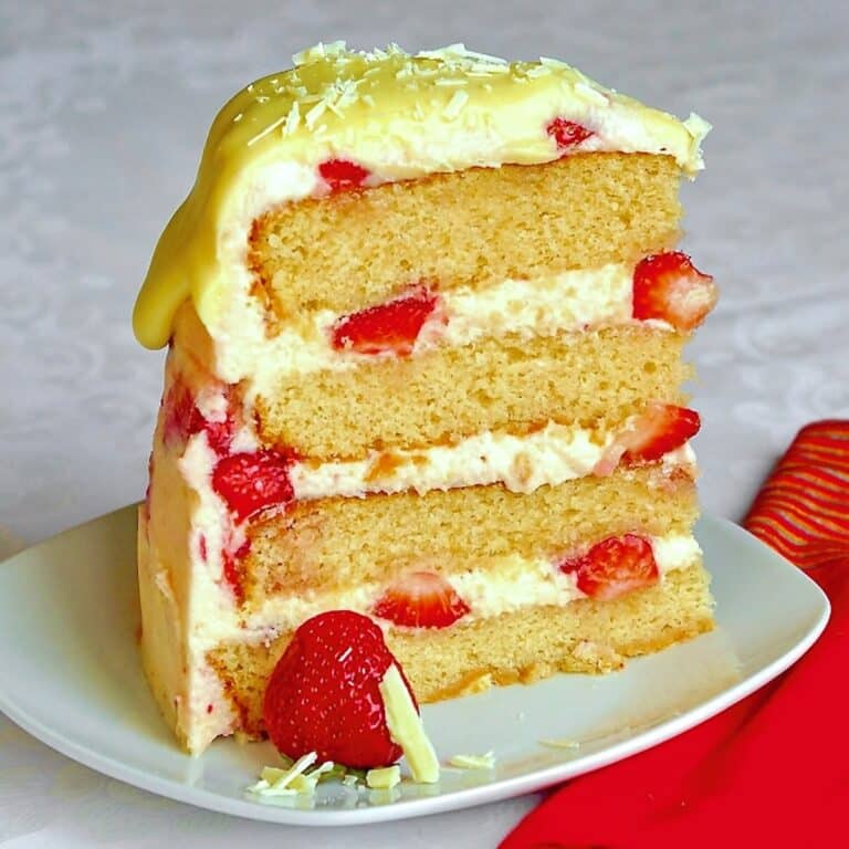 One slice if Strawberry White Chocolate Buttercream Cake on a white plate.