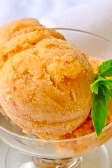 Amaretto Peach Sorbet, photo of one serving in a clear glass pedestal dessert dish.