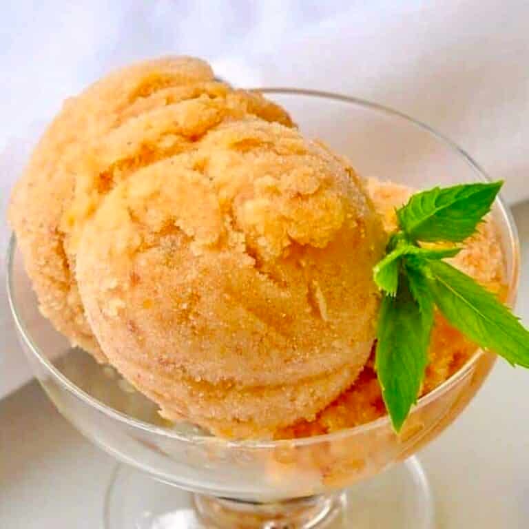 Amaretto Peach Sorbet, photo of one serving in a clear glass pedestal dessert dish.