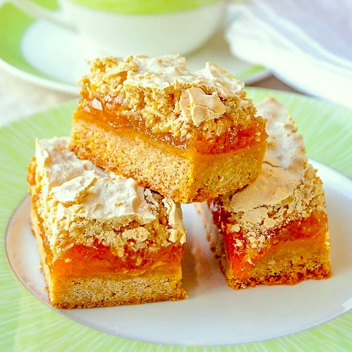 Apricot Coconut Meringue Bars shown with a green and white tea service.
