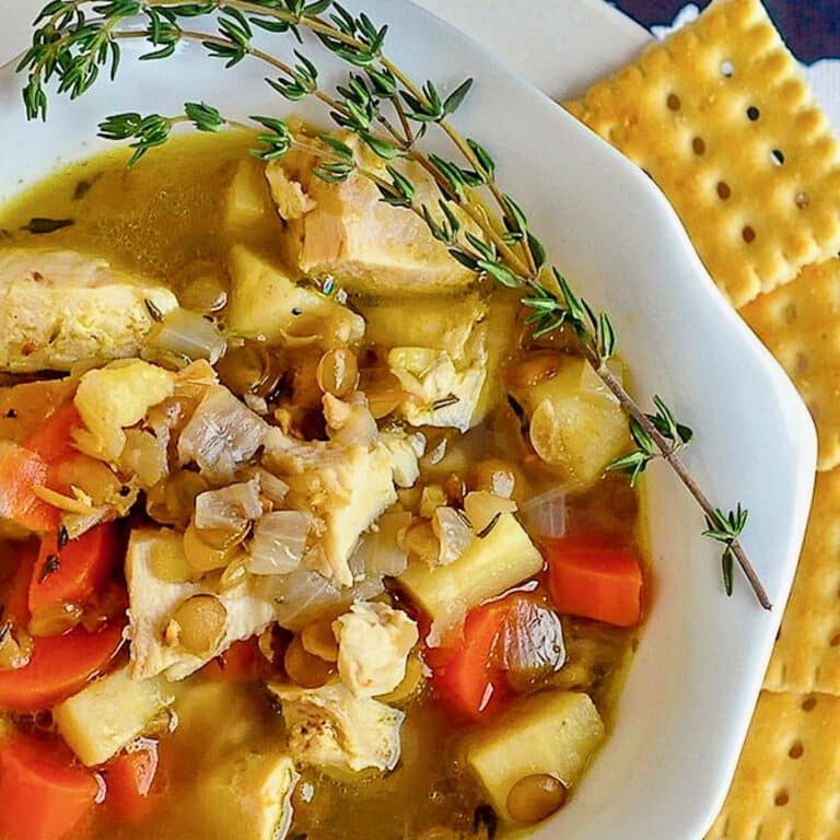 Chicken Thyme and Lentil Soup close up image of soup in a white bowl with crackers on the side