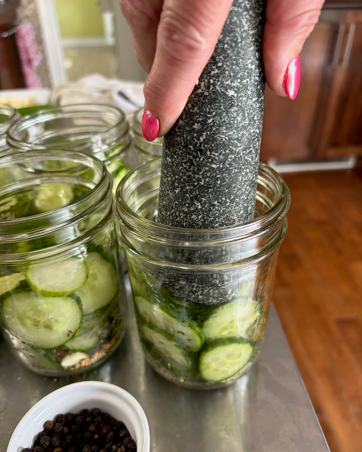 Photo of a stone pestle tamping cucumbers in a bottle