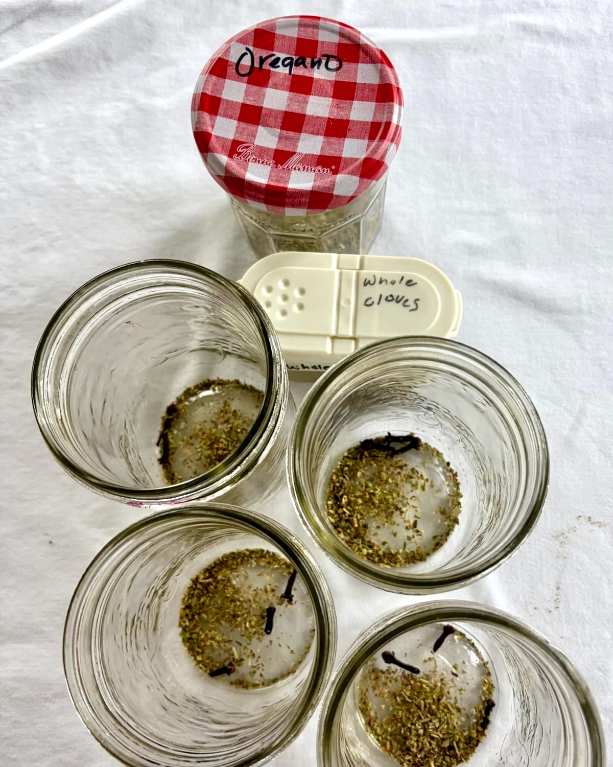 Photo of cloves and oregano added to the bottles.