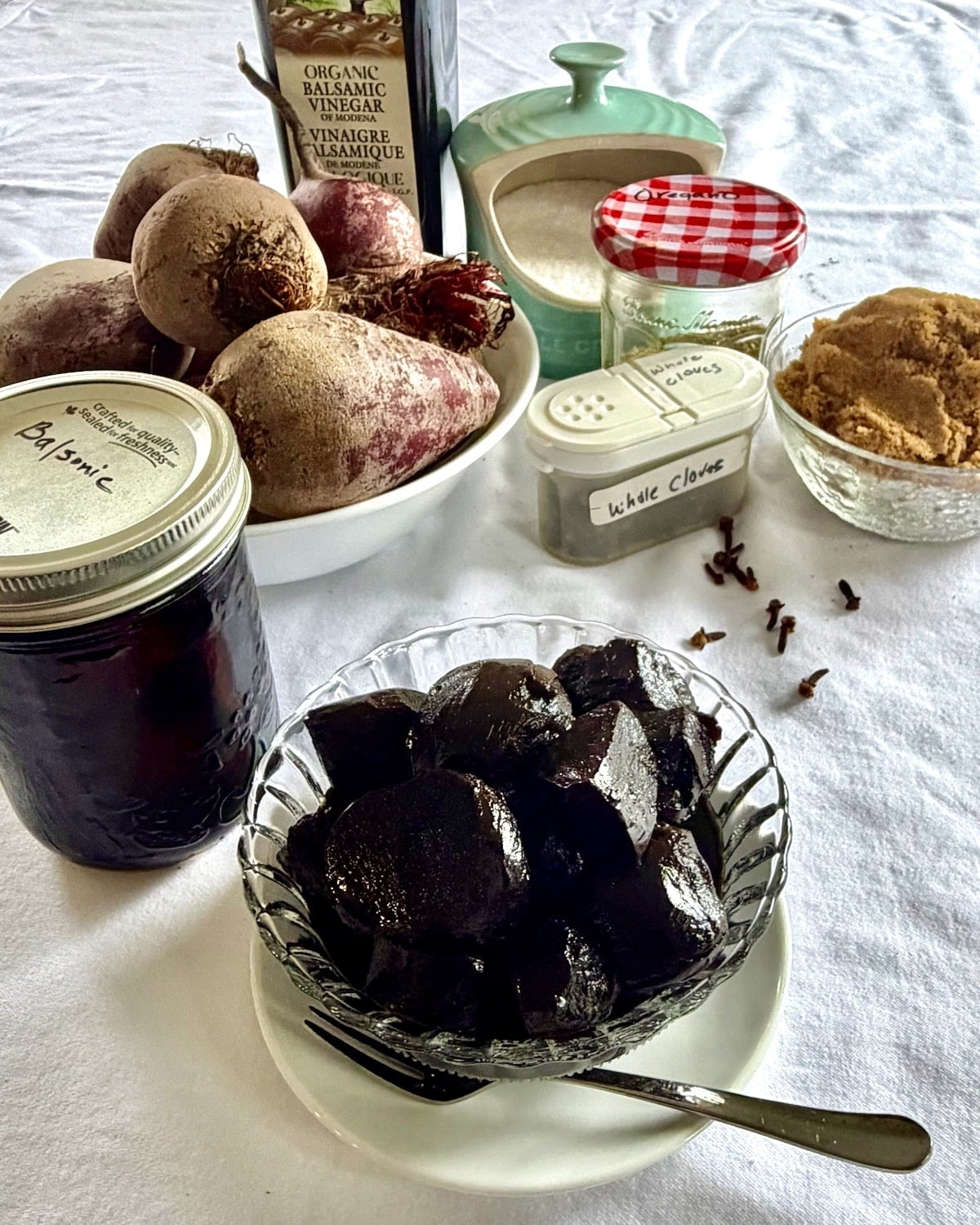 Balsamic Pickled Beets in a clear glass antique serving dish, with ingredients in the background.