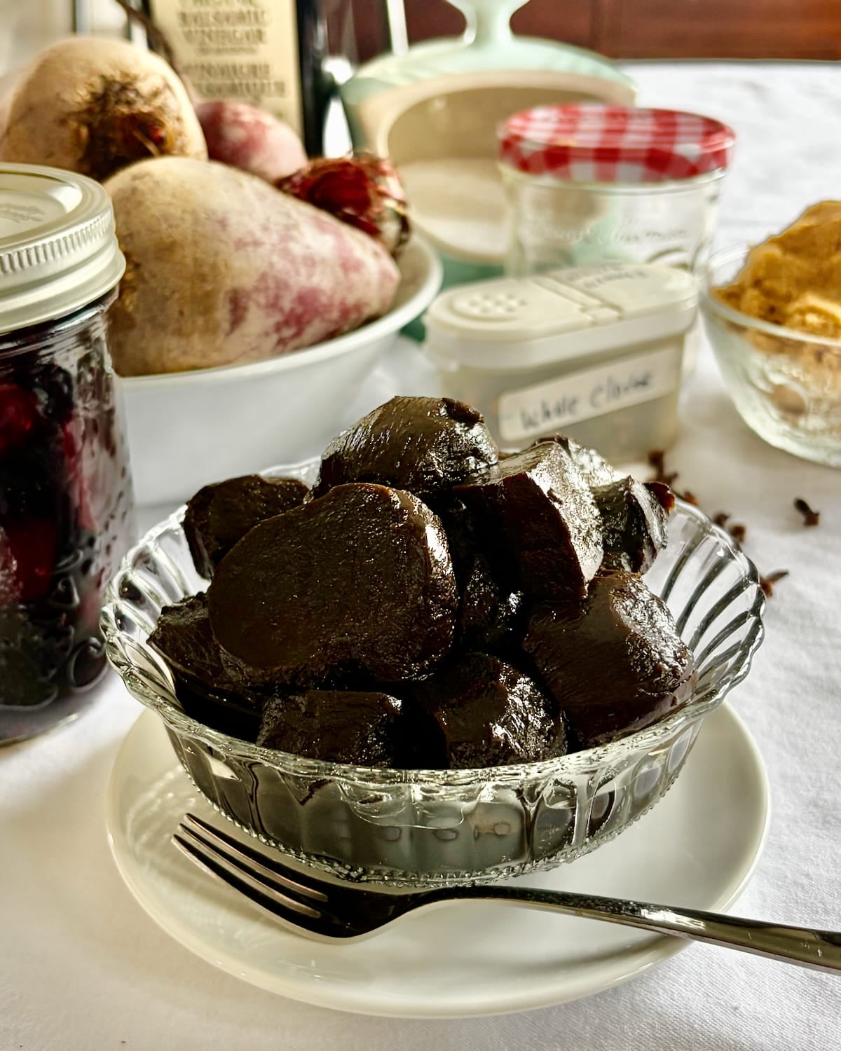 Balsamic Pickled Beets in a clear glass antique serving dish, with ingredients in the background.