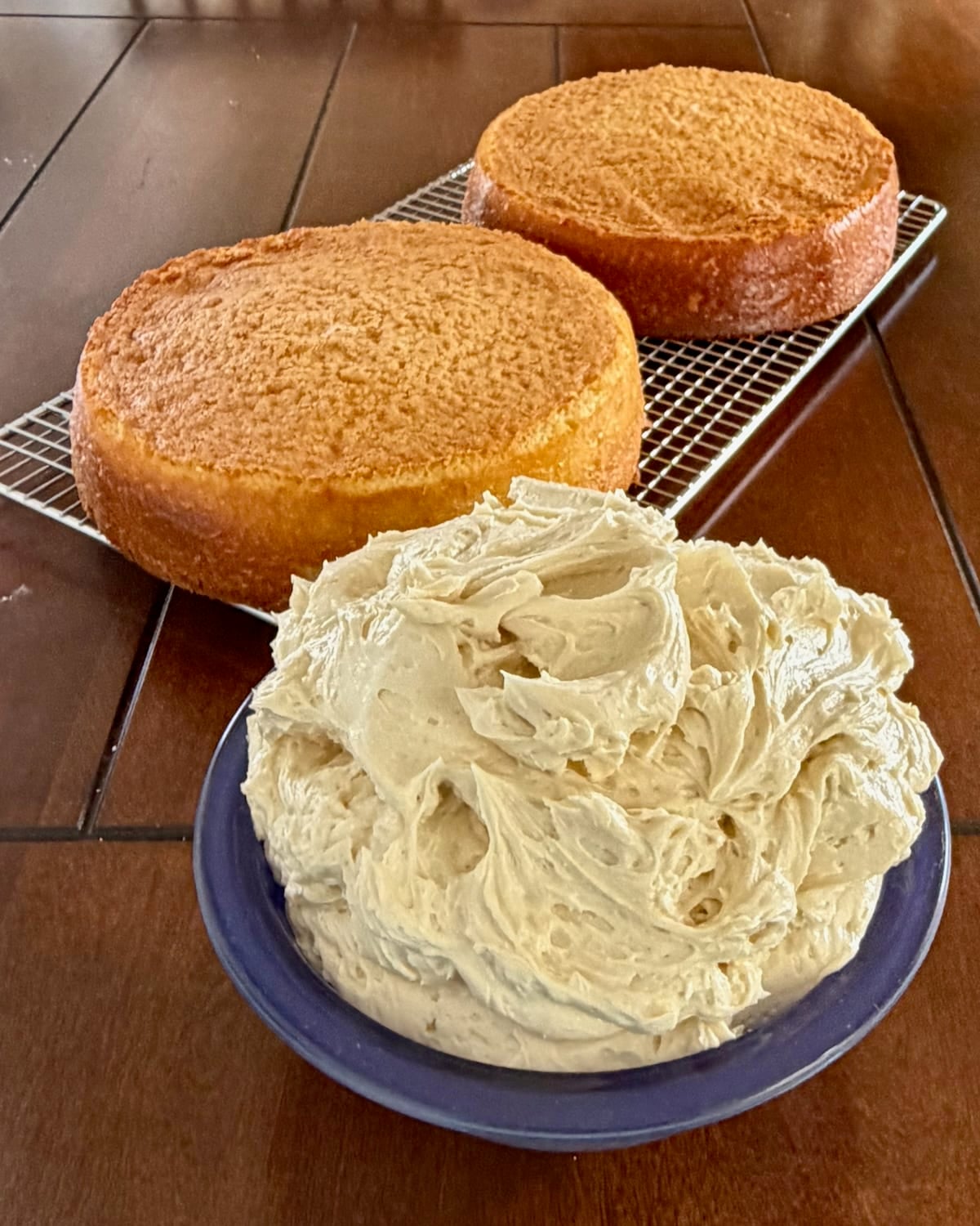 Photo of Ermine Cream Frosting in a blue bowl with vanilla cake in the background.