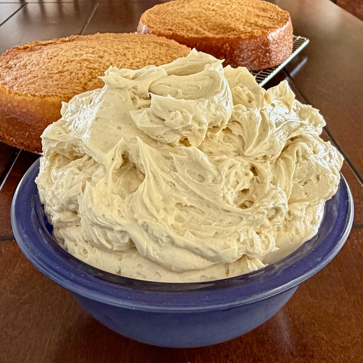 Close up Photo of Ermine Cream Frosting in a blue bowl with vanilla cake in the background.