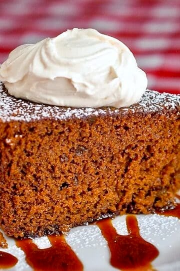 Triple Ginger Gingerbread Cake photo of a single slice topped by thick cream
