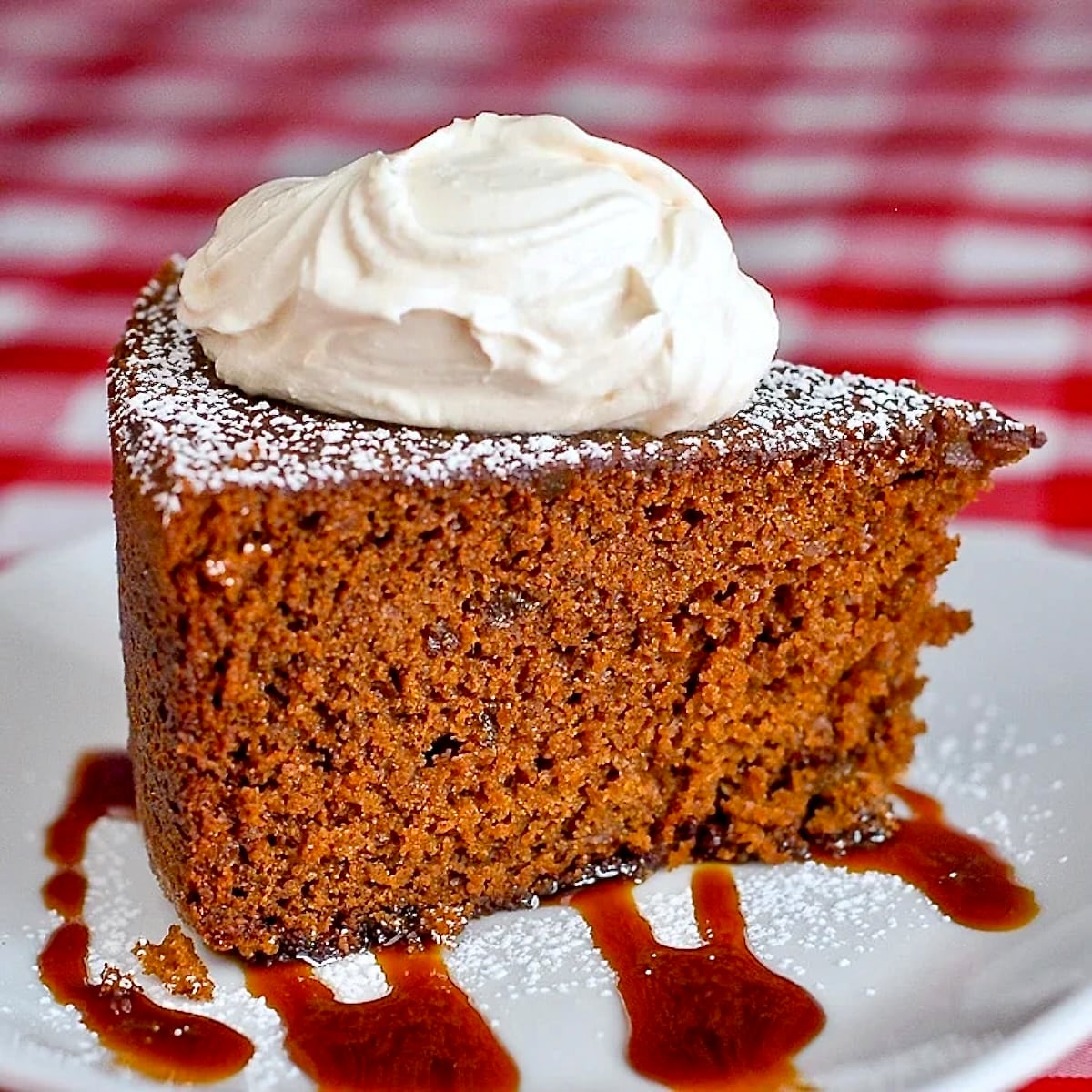 Triple Ginger Gingerbread Cake photo of a single slice topped by thick cream