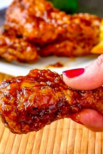 Close up photo of Crispy Orange Ginger Wings held between fingers