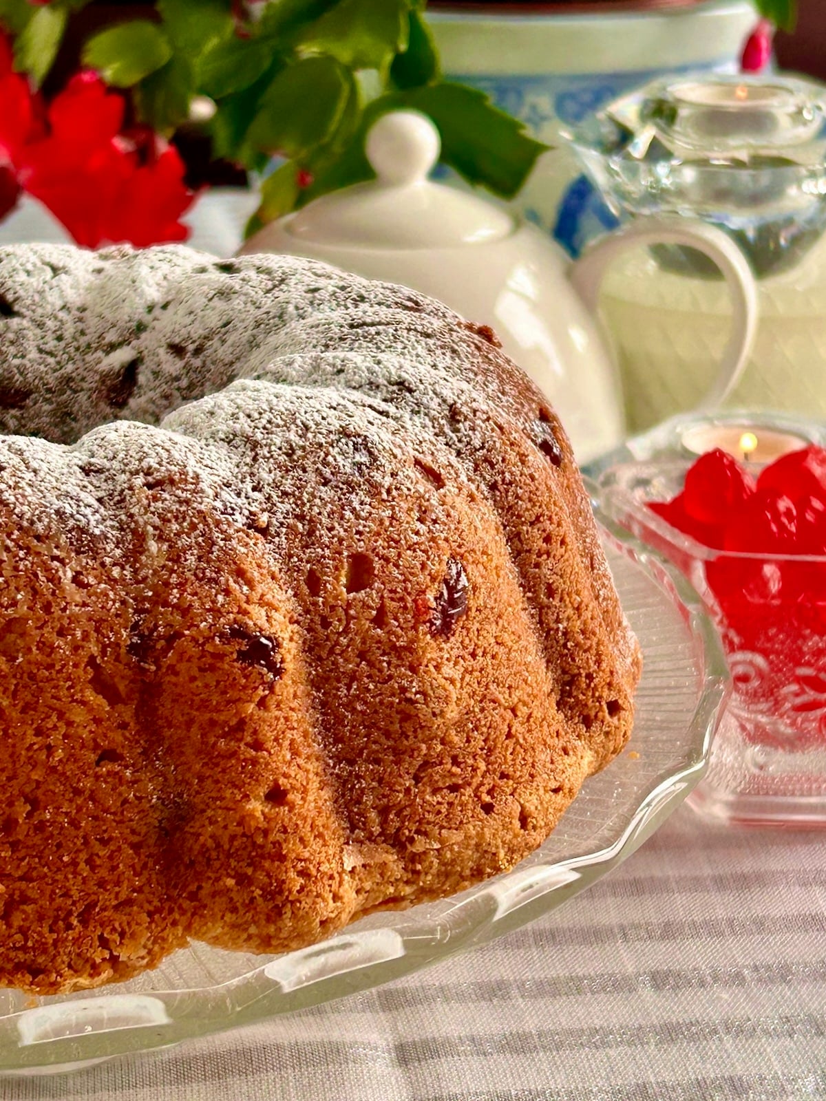 Close up photo of an uncut Swedish Berry Pound Cake on a glass pedestal formatted size for social media posts.