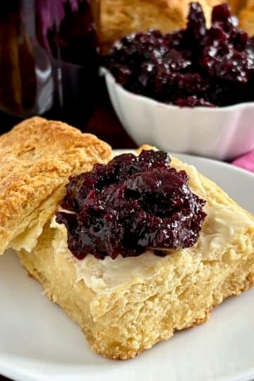 Close up photo of Low Sugar Blueberry Cherry Jam. on a biscuit.