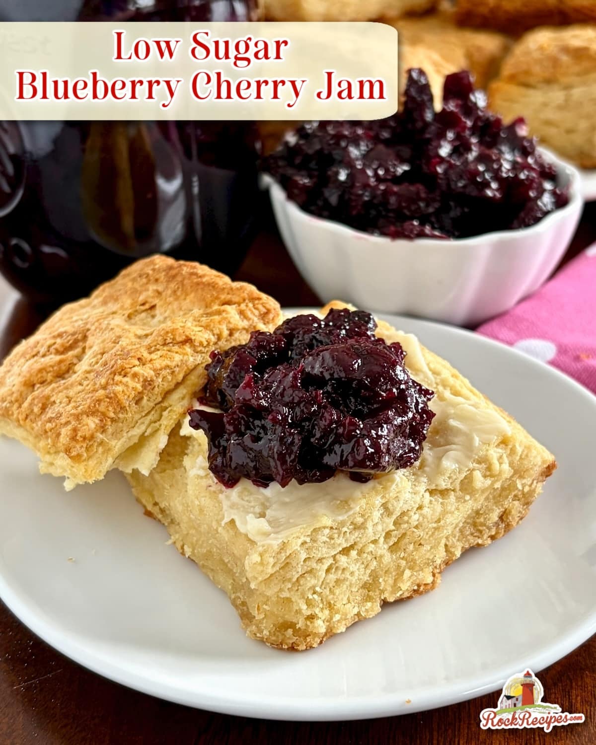 photo of Low Sugar Blueberry Cherry Jam.on a sour cream biscuit with title text added for scial media posts.