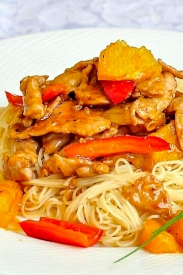 Spicy Honey Orange Sliced Pork close up photo of single serving on white plate.