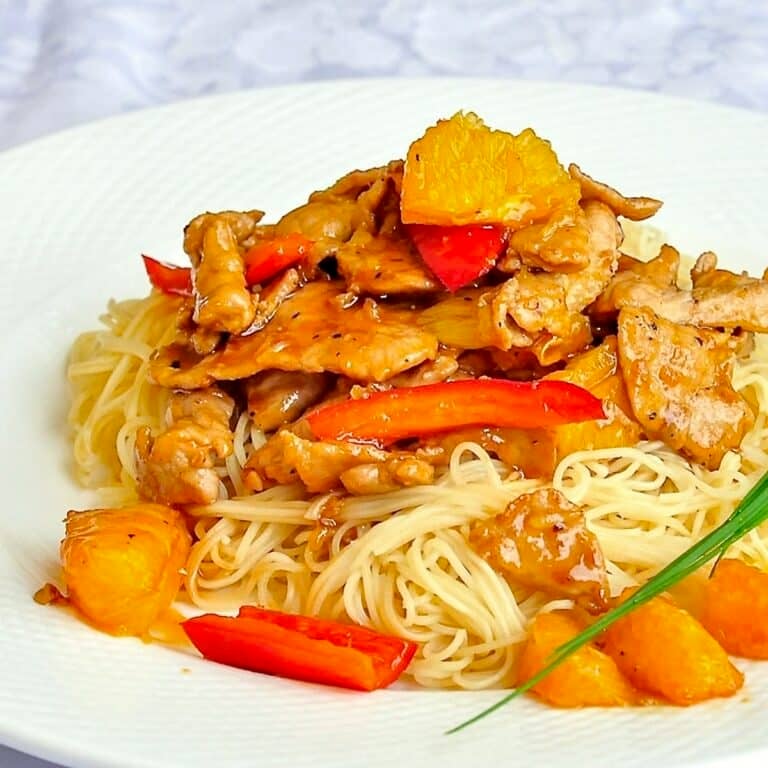 Spicy Honey Orange Sliced Pork close up photo of single serving on white plate.